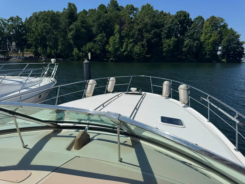 Slide: The Image of 2001 Sea Ray 380 Sundancer yacht on calm water near lush green shoreline. - 13