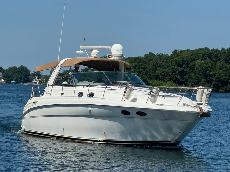 Slide: The Image of 2001 Sea Ray 380 Sundancer yacht cruising on a serene lake with lush green shoreline. - 2