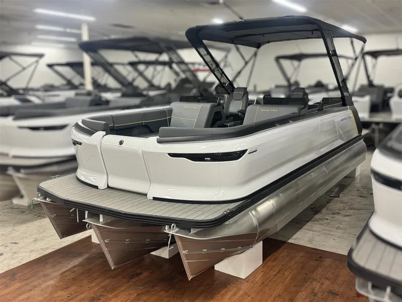 The Image of 2025 Manitou Explore 24 Navigator pontoon boat in showroom, featuring sleek design and modern seating. - 0