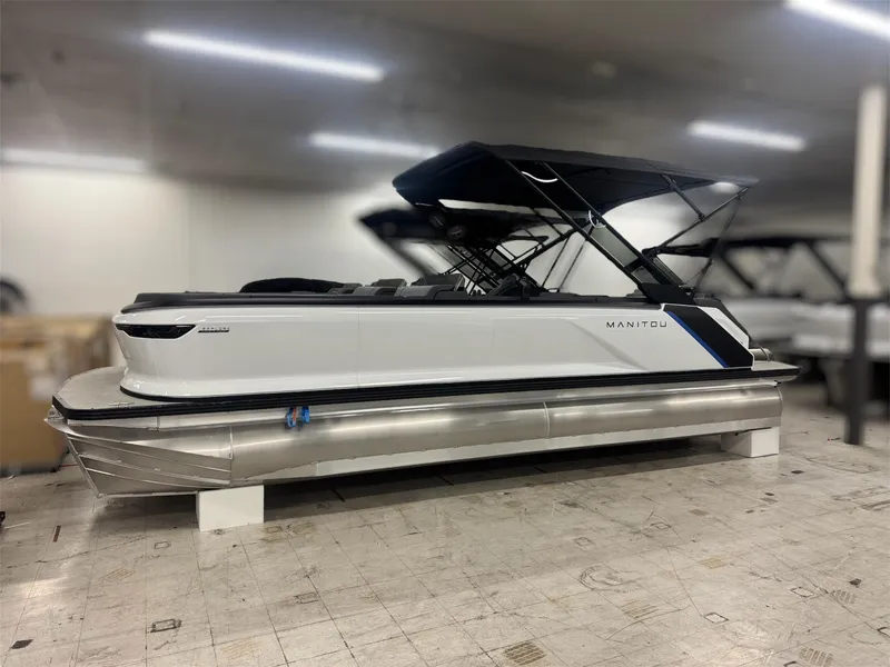 Slide: The Image of 2025 Manitou Explore 24 Navigator pontoon boat in showroom, side view. - 3
