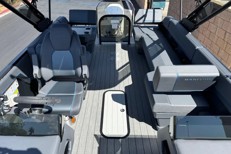 Slide: The Image of 2025 Manitou Explore 24 Navigator boat interior with modern seating and steering. - 12