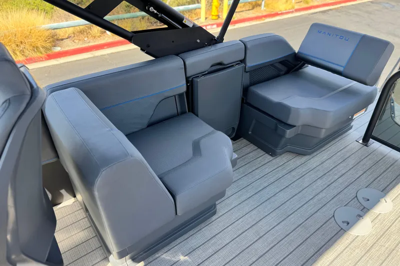 Slide: The Image of Interior seating of 2025 Manitou Explore 24 Navigator boat, featuring modern gray upholstery. - 14