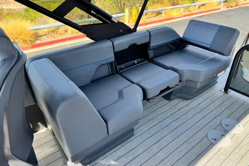 Slide: The Image of 2025 Manitou Explore 24 Navigator boat interior with sleek gray seating and modern design. - 15