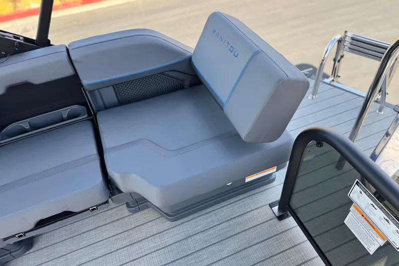 Slide: The Image of 2025 Manitou Explore 24 Navigator boat seating with sleek gray upholstery and blue stitching. - 16