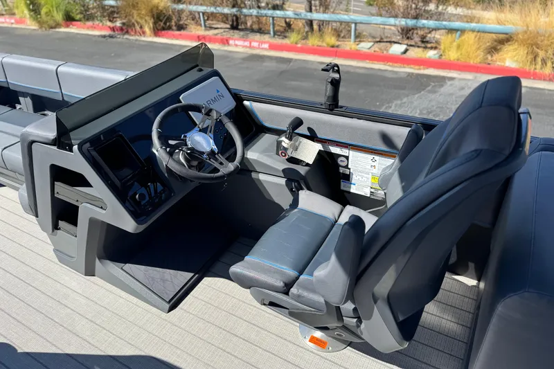 Slide: The Image of 2025 Manitou Explore 24 Navigator boat cockpit with steering wheel and seating. - 24