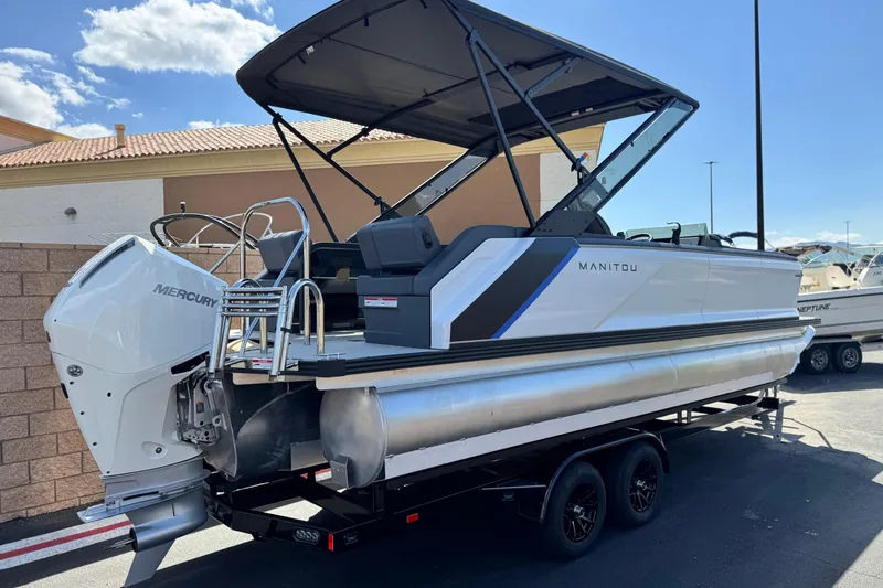Slide: The Image of 2025 Manitou Explore 24 Navigator pontoon boat with Mercury engine, parked on trailer. - 6