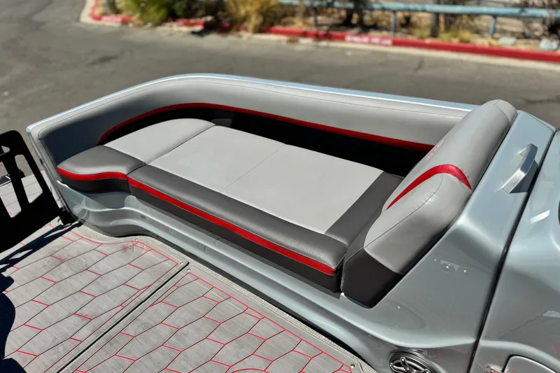 Slide: The Image of 2023 Manitou 25 XT RFXW boat seat with gray and red upholstery, outdoor setting. - 14