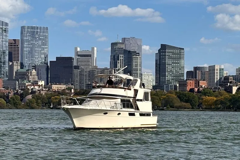 The Image of 1987 Californian 48 Cockpit Motor Yacht cruising near city skyline on a sunny day. - 0