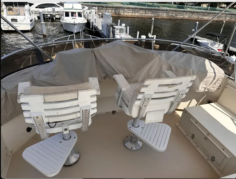 Slide: The Image of 1987 Californian 48 Cockpit Motor Yacht with two white chairs on deck, docked at marina. - 23