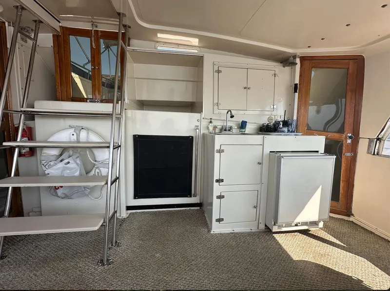 Slide: The Image of 1987 Californian 48 Cockpit Motor Yacht interior with kitchenette, ladder, and wooden doors. - 25