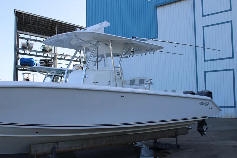 Slide: The Image of 1998 Venture 34 Open boat docked near a blue and white building. - 3