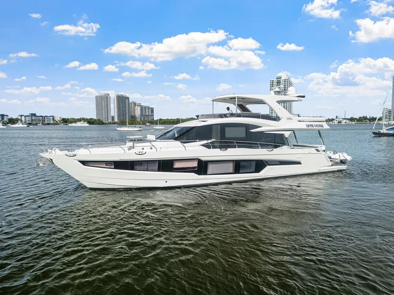 Slide: The Image of 2021 Galeon 680 Fly yacht cruising on a sunny day with city skyline backdrop. - 26