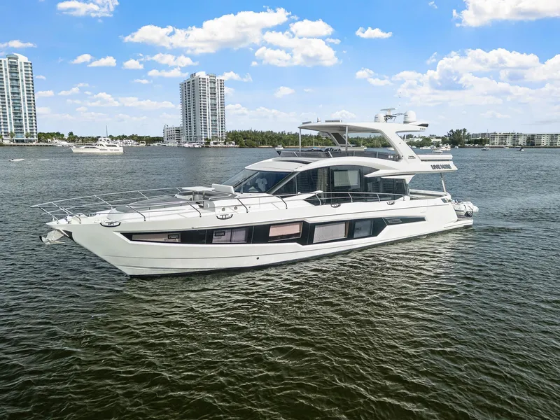Slide: The Image of 2021 Galeon 680 Fly yacht cruising on a sunny day with city skyline backdrop. - 38