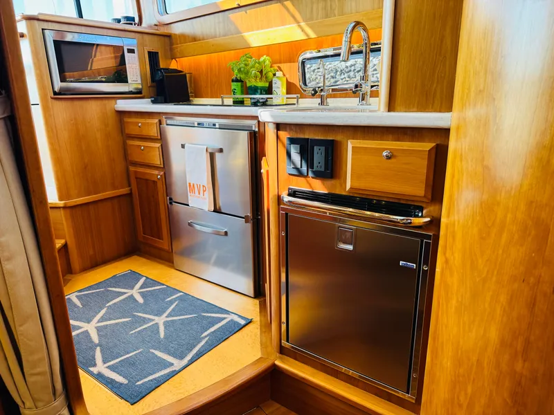 Slide: The Image of 2018 Sabre 42 Salon Express kitchen with wood cabinetry, stainless appliances, and nautical decor. - 11
