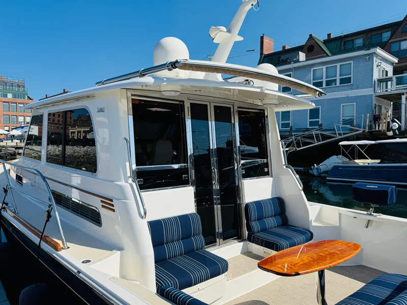 Slide: The Image of 2018 Sabre 42 Salon Express yacht with striped seating and wooden table, docked at marina. - 5