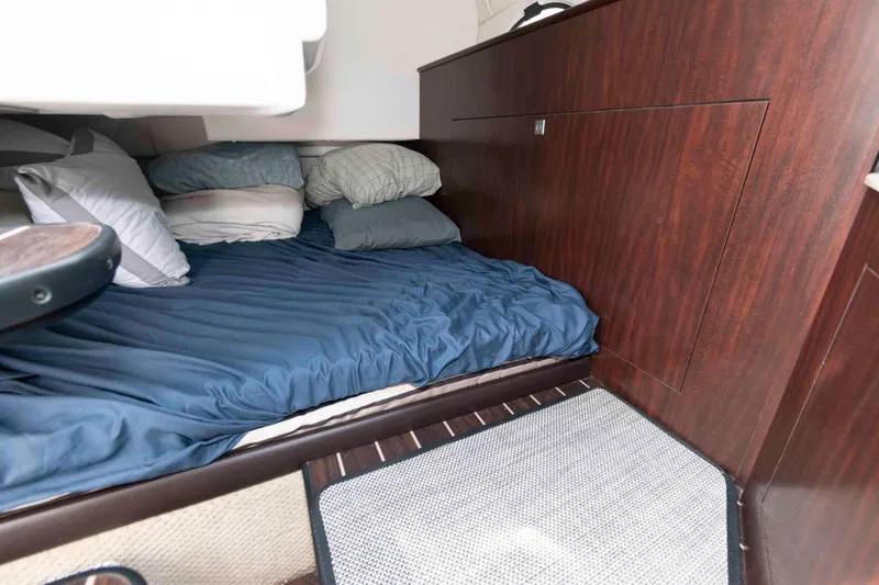 Slide: The Image of 2018 Monterey 295 Sport Yacht cabin with cozy bed and pillows, featuring elegant wood paneling. - 16