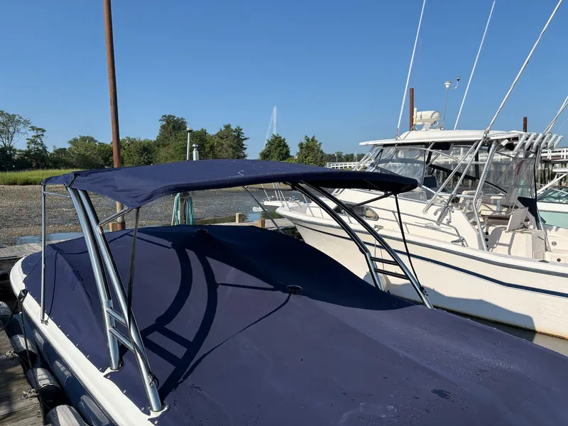 Slide: The Image of 2012 Cobalt A28 boat with blue canopy docked beside other boats. - 15