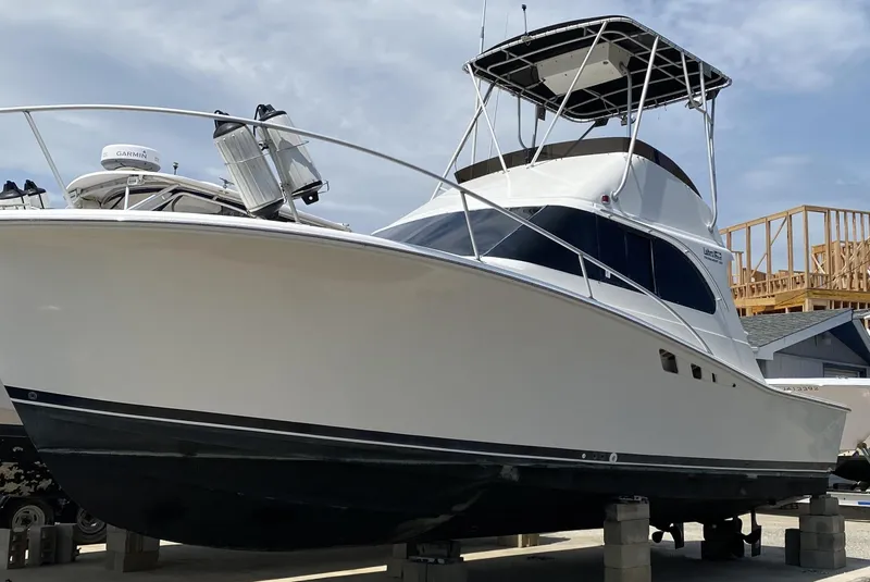 Slide: The Image of 1992 Luhrs Tournament 320 Convertible boat on dry dock, featuring a sleek white hull. - 12