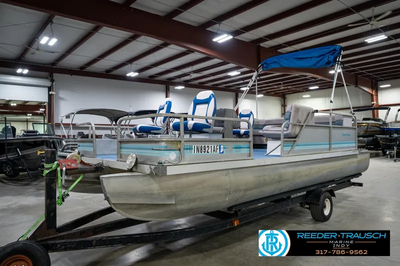 Slide: The Image of 1988 Landau 20 Adventurer pontoon boat with blue and white seating, displayed indoors. - 10