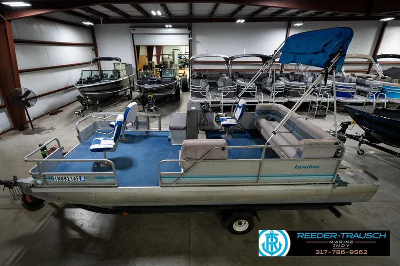 Slide: The Image of 1988 Landau 20 Adventurer pontoon boat with blue and white seating, displayed indoors. - 11