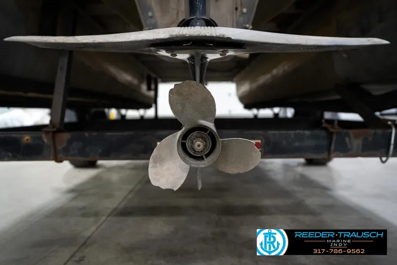 Slide: The Image of 1988 Landau 20 Adventurer boat interior with blue carpet and steering console in a garage. - 16