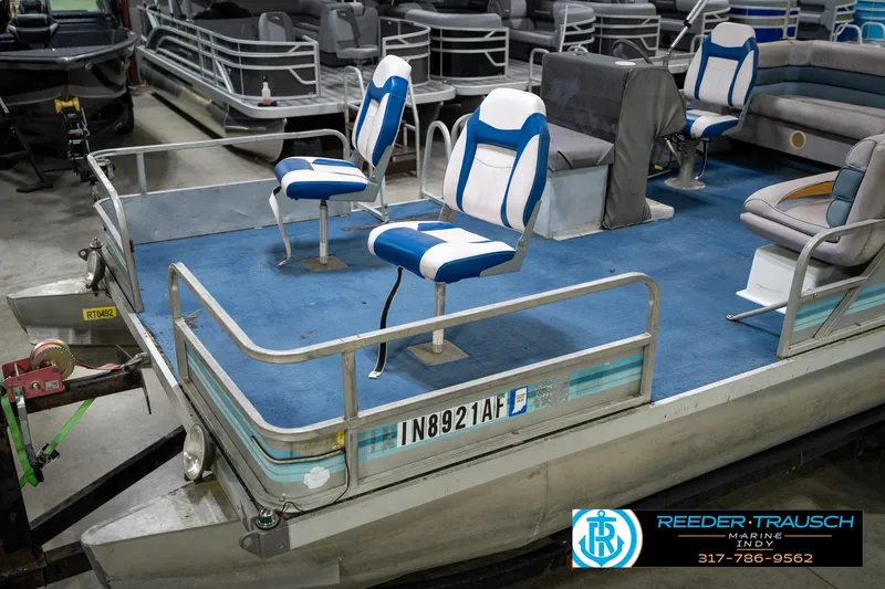 Slide: The Image of 1988 Landau 20 Adventurer boat interior with two white and blue seats in a garage. - 17