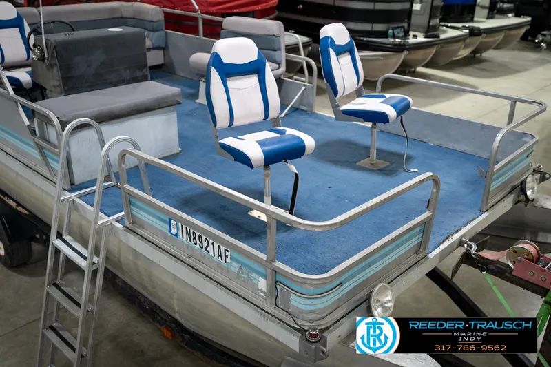 Slide: The Image of 1988 Landau 20 Adventurer boat interior with blue carpet and two white seats in a garage. - 18