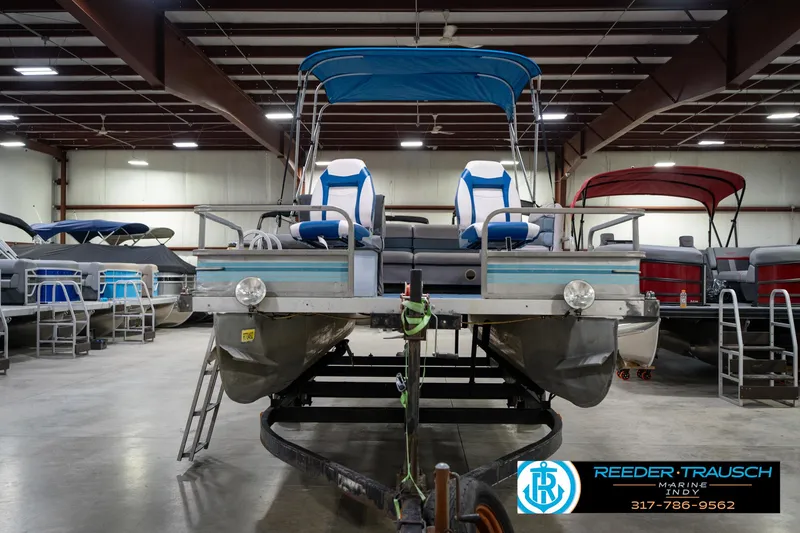 Slide: The Image of 1988 Landau 20 Adventurer pontoon boat in showroom with blue canopy and seating. - 3