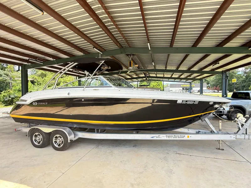 Slide: The Image of 2012 Cobalt 276 boat on trailer under metal roof, side view. - 2
