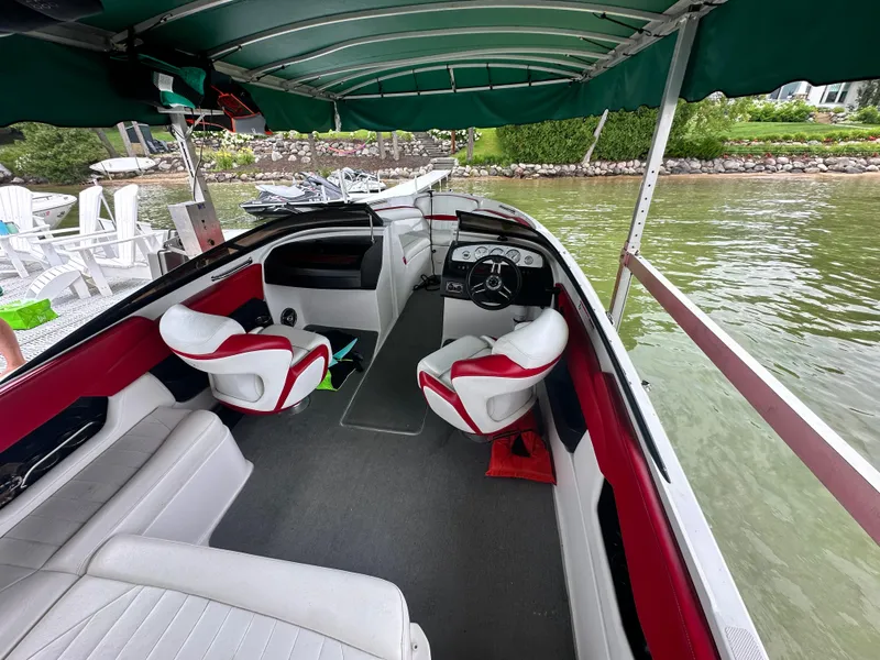 Slide: The Image of 2008 Regal 2200 RS boat interior with red and white seating under a green canopy. - 11