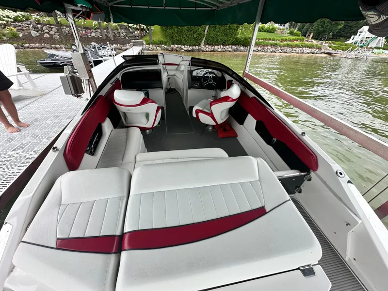 Slide: The Image of 2008 Regal 2200 RS boat interior with white and red seating, docked by a lake. - 12