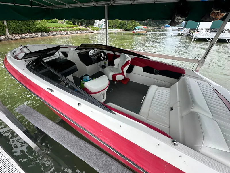 Slide: The Image of 2008 Regal 2200 RS boat with red and white interior, docked by a lakeside. - 13