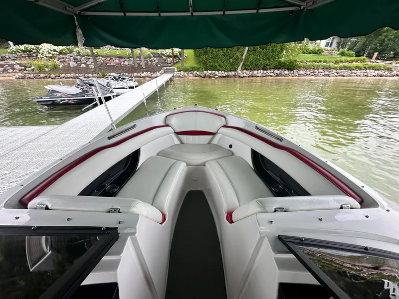 Slide: The Image of 2008 Regal 2200 RS boat interior with white and red seating, docked by a lakeside. - 5
