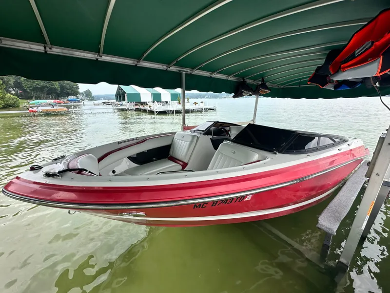 Slide: The Image of 2008 Regal 2200 RS boat docked under a green canopy on a lake. - 6