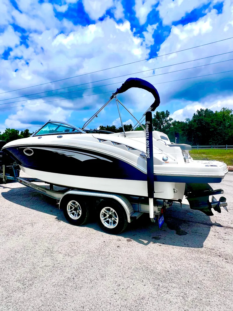 Slide: The Image of 2015 Chaparral 224 Sunesta boat on trailer, blue and white design, parked outdoors. - 4