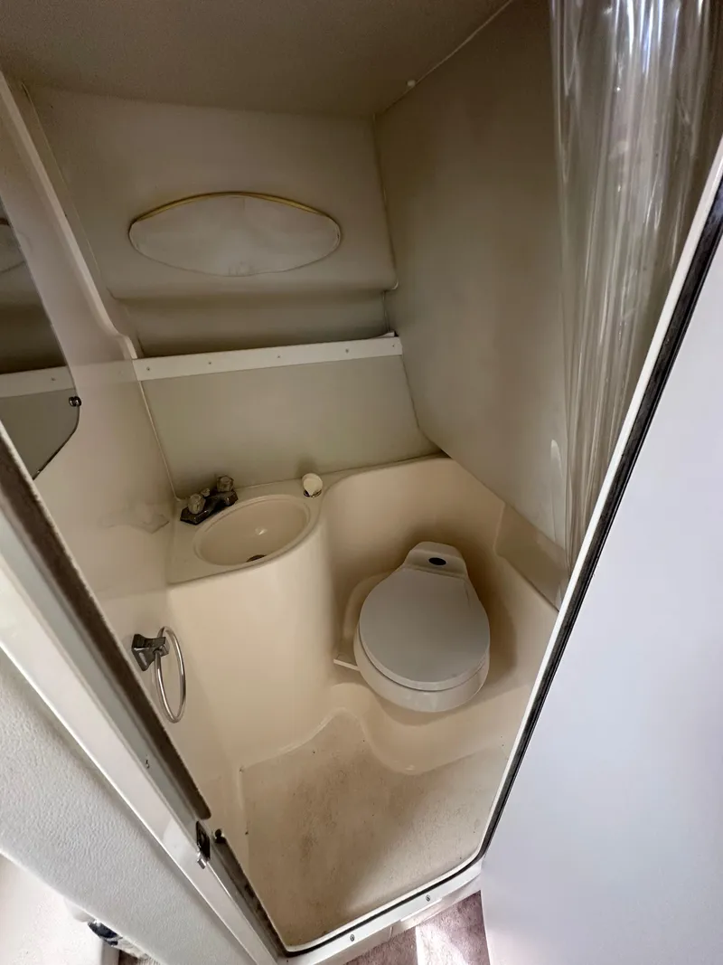 Slide: The Image of Compact bathroom in a 1998 Wellcraft 260 boat, featuring a toilet and sink. - 7