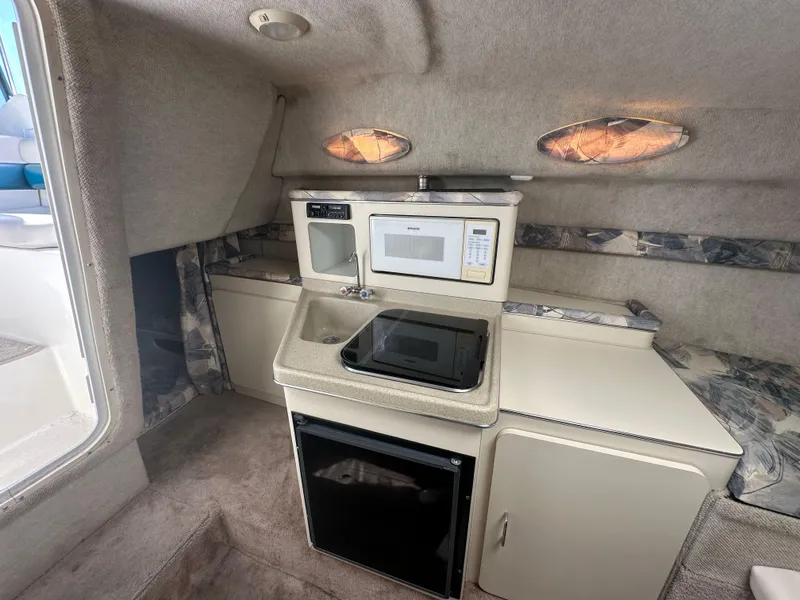 Slide: The Image of Interior of a 1998 Wellcraft 260 boat featuring a kitchenette with microwave and sink. - 8