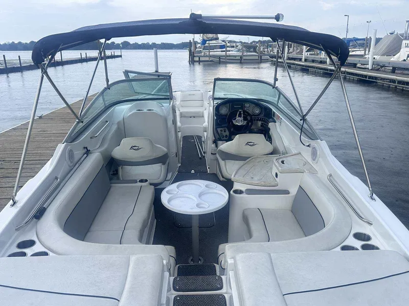 Slide: The Image of 2015 Rinker 276 Captiva Bowrider interior with seating, table, and helm at a dock. - 14