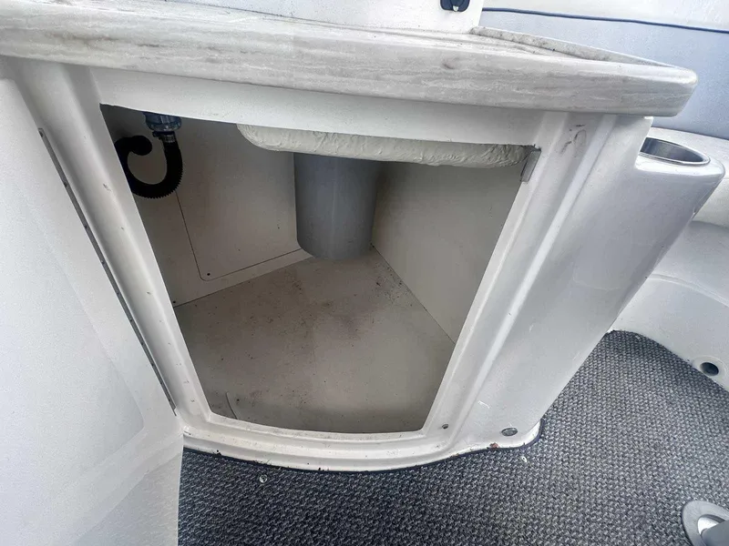 Slide: The Image of 2015 Rinker 276 Captiva Bowrider storage compartment with open door, showcasing interior space. - 18
