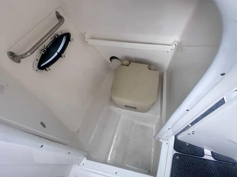 Slide: The Image of 2015 Rinker 276 Captiva Bowrider boat bathroom with portable toilet and porthole window. - 26
