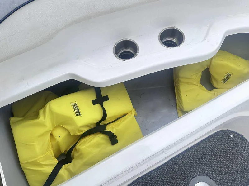 Slide: The Image of Yellow life jackets stored in a 2015 Rinker 276 Captiva Bowrider boat compartment. - 32