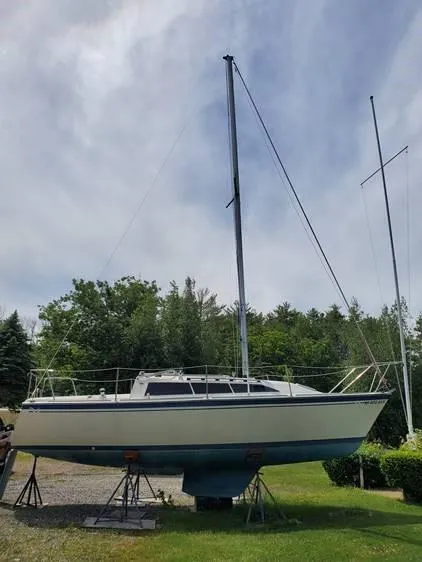 Slide: The Image of 1987 O'Day 272 sailboat on stands, surrounded by greenery and a cloudy sky. - 2