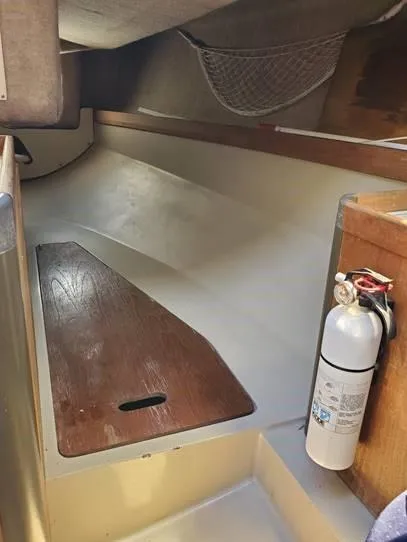 Slide: The Image of Interior of a 1987 O'Day 272 sailboat, featuring a wooden bench and fire extinguisher. - 22