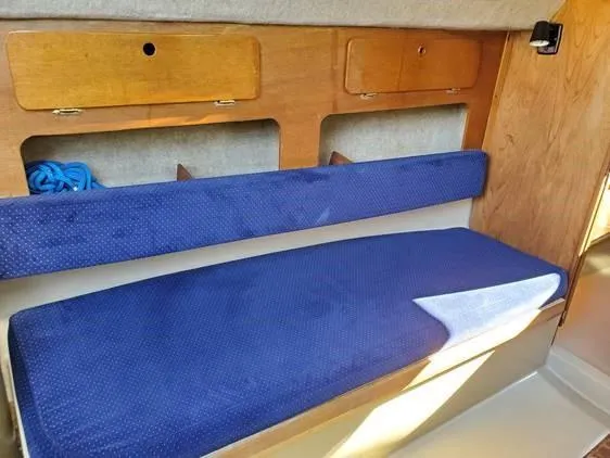 Slide: The Image of Interior of 1987 O'Day 272 sailboat with blue cushioned seating and wooden storage compartments. - 25
