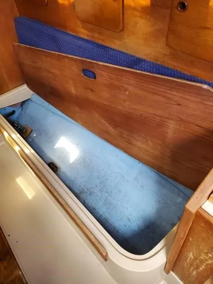 Slide: The Image of 1987 O'Day 272 sailboat interior storage compartment with wooden paneling and blue lining. - 27