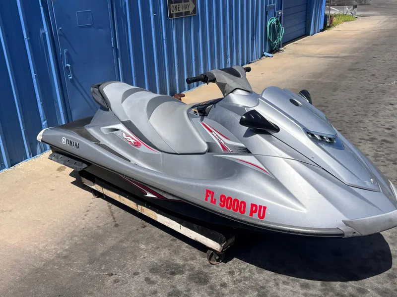 The Image of 2014 Yamaha WaveRunner VXR jet ski parked by a blue building. - 5