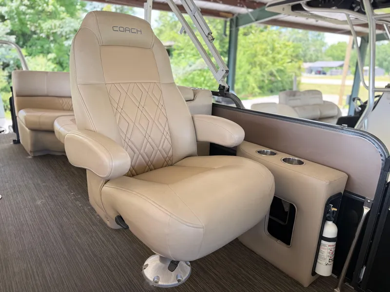 Slide: The Image of Luxurious seating on a 2016 Coach Pontoons 25RF, featuring beige upholstery and cup holders. - 11