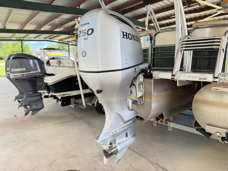 Slide: The Image of 2016 Coach Pontoons 25RF with Honda 250 VTEC outboard motor in a covered area. - 4