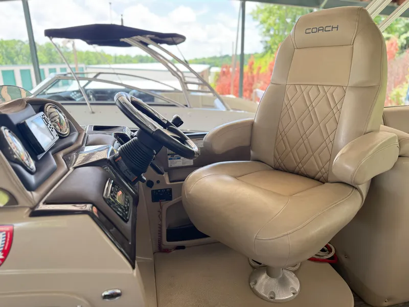 Slide: The Image of Captain's chair and dashboard of 2016 Coach Pontoons 25RF boat, featuring luxurious design. - 6