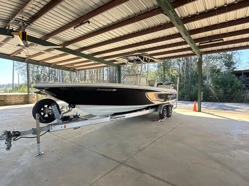 Slide: The Image of 2013 Blackwood 27 boat on trailer under metal canopy, surrounded by trees. - 4
